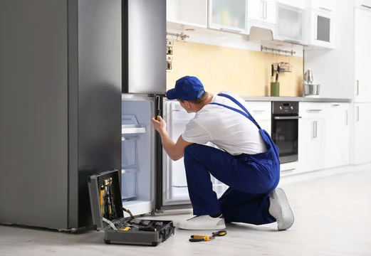 Technician working beside a refrigerator in a home kitchen