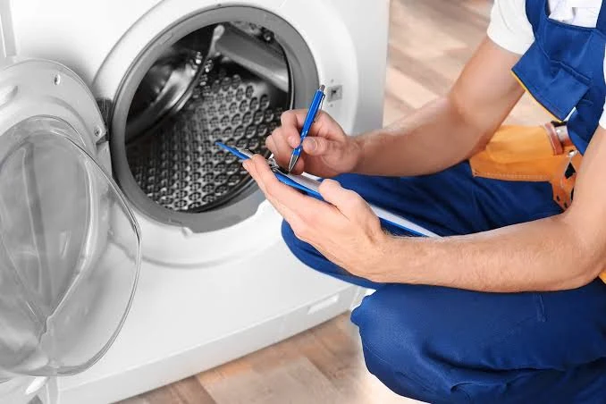 Technician recording notes beside an open washing machine drum