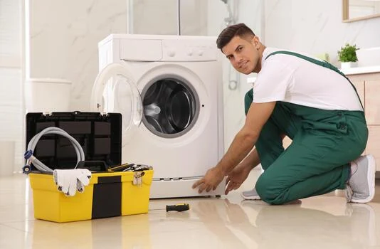 Technician beside a washing machine with a service toolkit